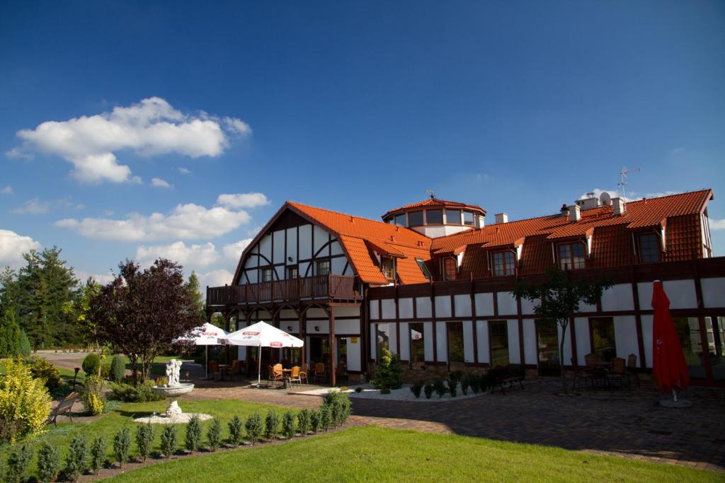 Gogolin卡罗林卡酒店的一座带橙色屋顶的大型建筑,设有庭院