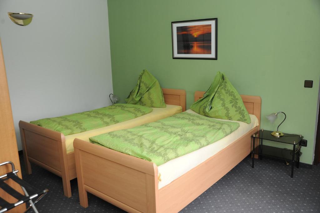 维也纳Pension Erlaa的配有绿床单的客房内的两张床