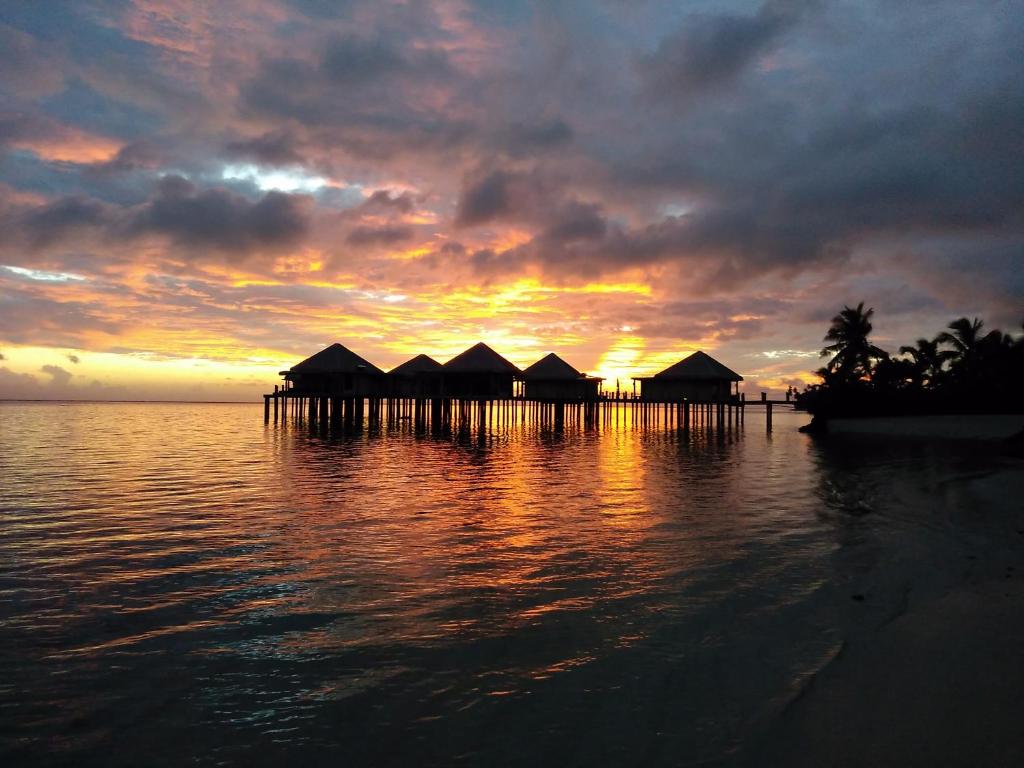 Fausaga椰子海滩俱乐部度假酒店&Spa的日落时分在水面上建一套小屋