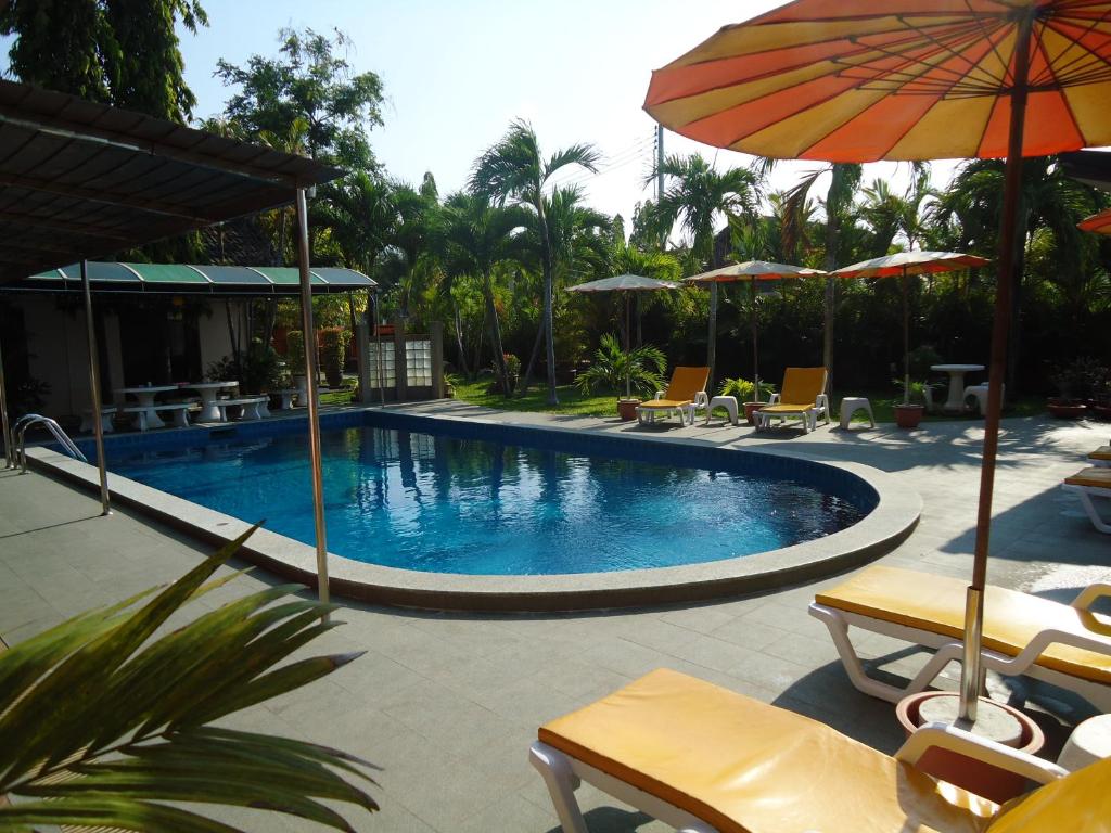 农布鲁诺普斯同性天堂酒店的一个带遮阳伞和椅子的游泳池以及一个度假村
