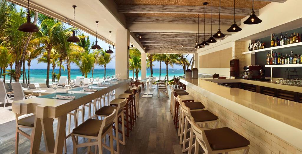西普哈加泰罗尼亚皇家图卢姆海滩Spa度假村 - 仅限成人 - 全包的餐厅设有酒吧,背景为大海