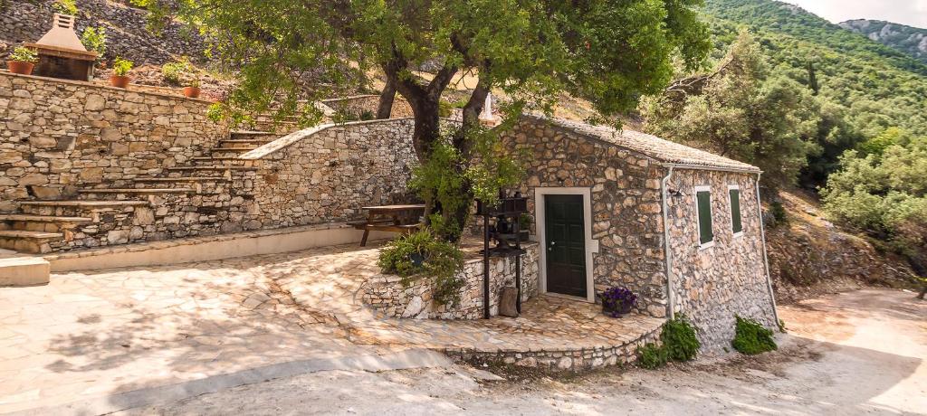阿查拉维Castelli Olive Press的一座小石头建筑,有树和楼梯