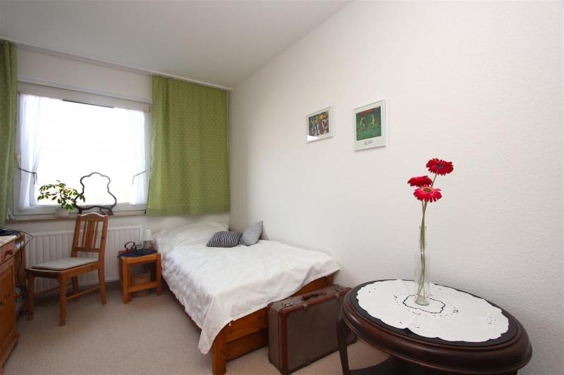 汉诺威Private Room的一间卧室配有一张床和一张桌子,上面有花瓶