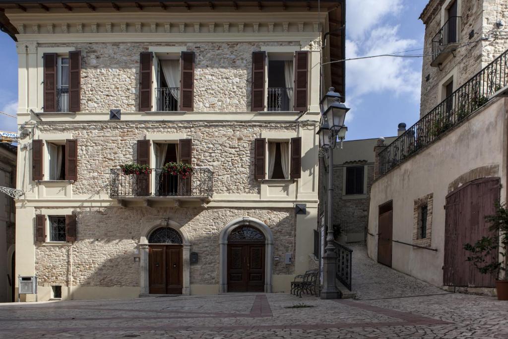 CugnoliDimora Il Palazzetto的一座古老的石头建筑,设有门和阳台