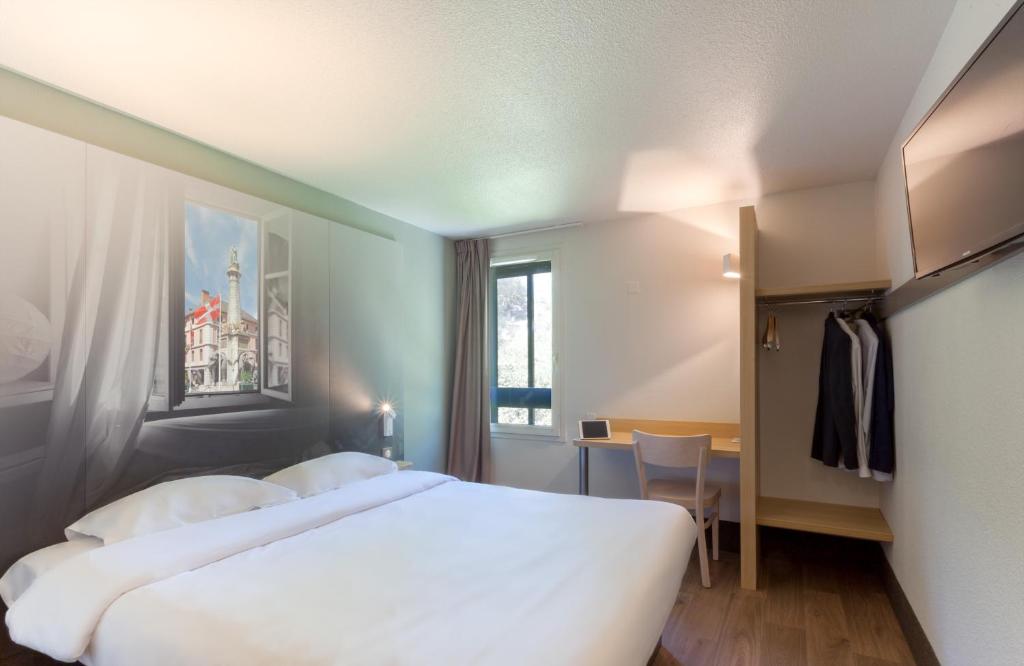 尚贝里B&B HOTEL CHAMBERY La Cassine的酒店客房设有两张床和窗户。