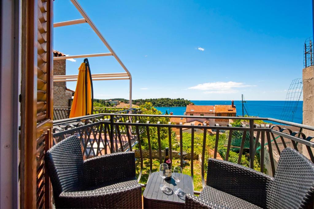 罗维尼Monte Holiday Home with Jacuzzi的阳台配有桌子和遮阳伞,享有海景。