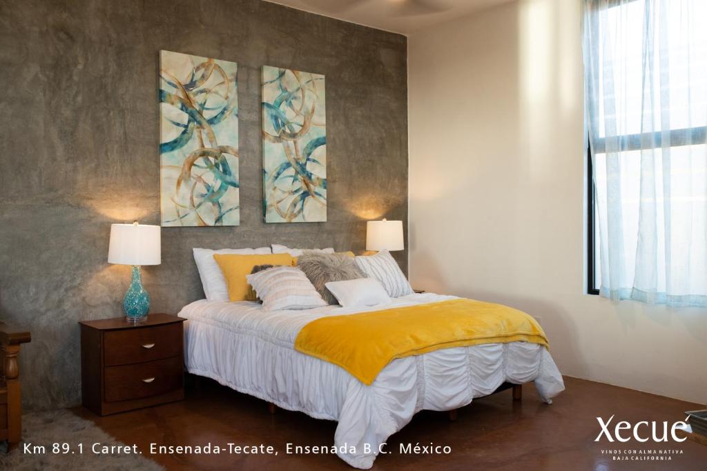 恩塞纳达港Vinos Xecué的卧室配有一张床,墙上挂有两幅画