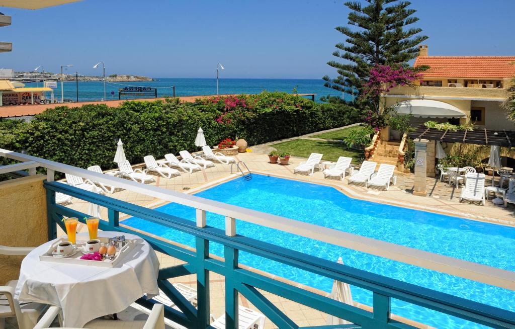 赫索尼索斯佩特拉海滩酒店的阳台的游泳池配有桌椅