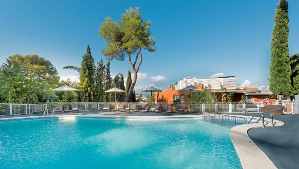 马略卡岛帕尔马Hesperia Ciudad de Mallorca的一座树木繁茂的大型游泳池和一座建筑