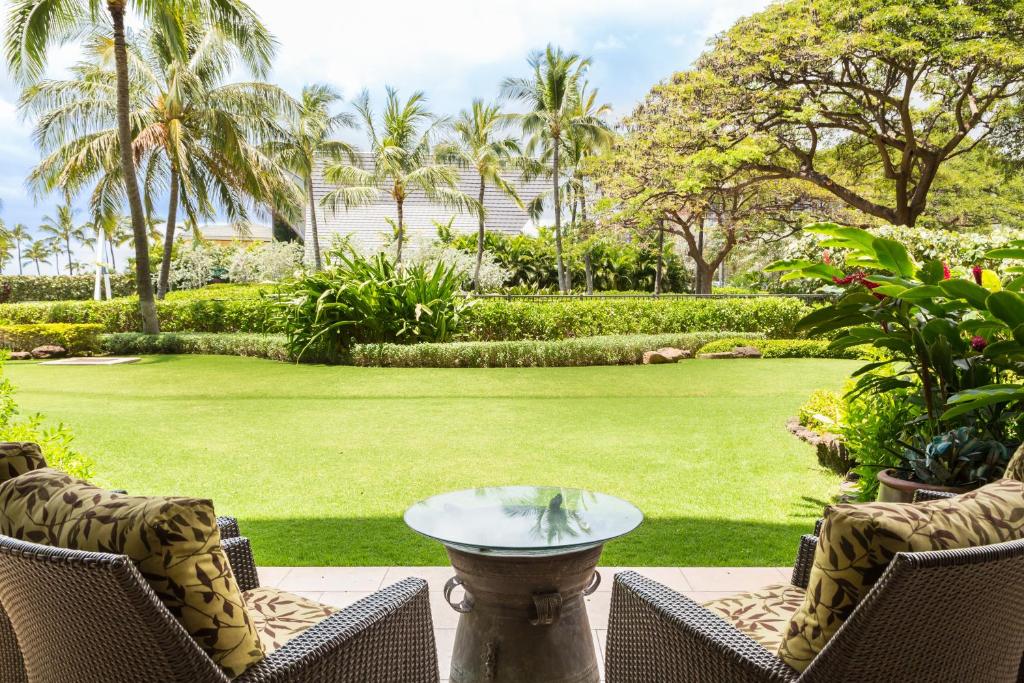 卡波雷Popular Ground Floor with Extra Grassy Area - Beach Tower at Ko Olina Beach Villas Resort的一个带桌椅的庭院和一个草坪