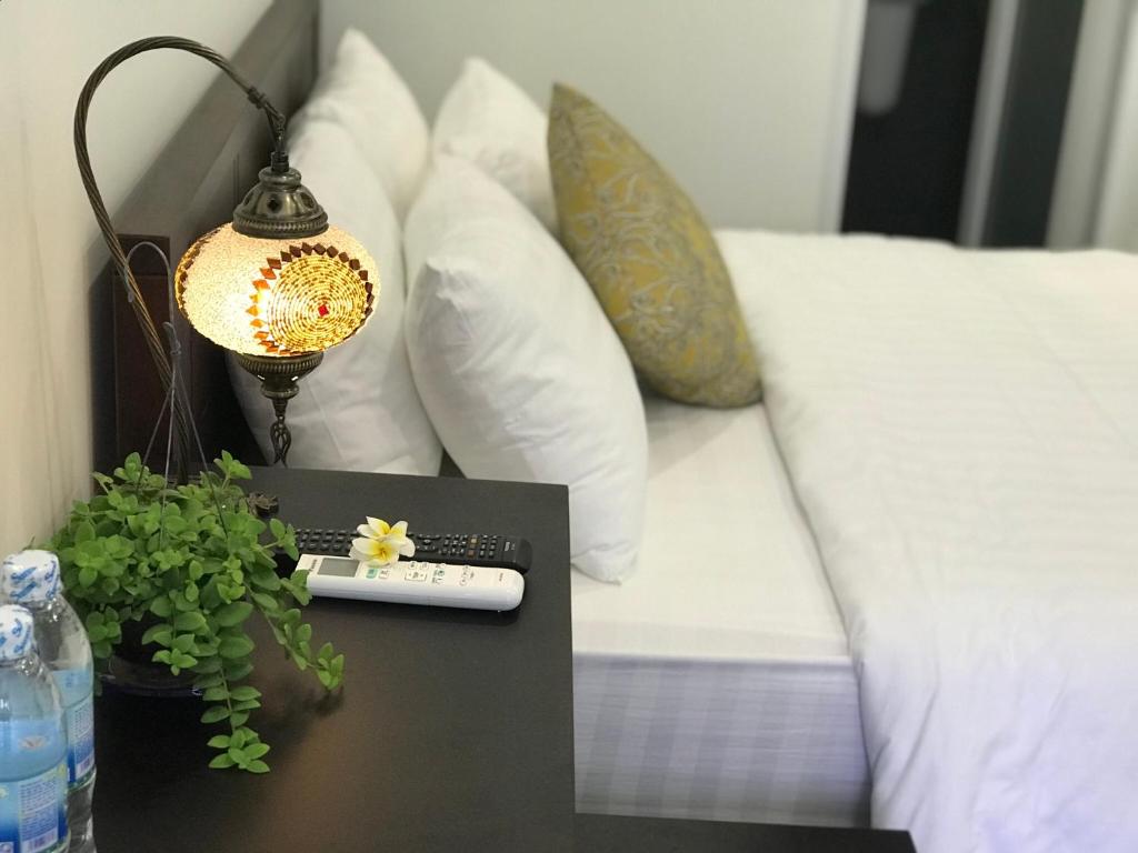 芽庄Moonlight House & Apartment Nha Trang的一张桌子,上面有遥控器,床上有台灯