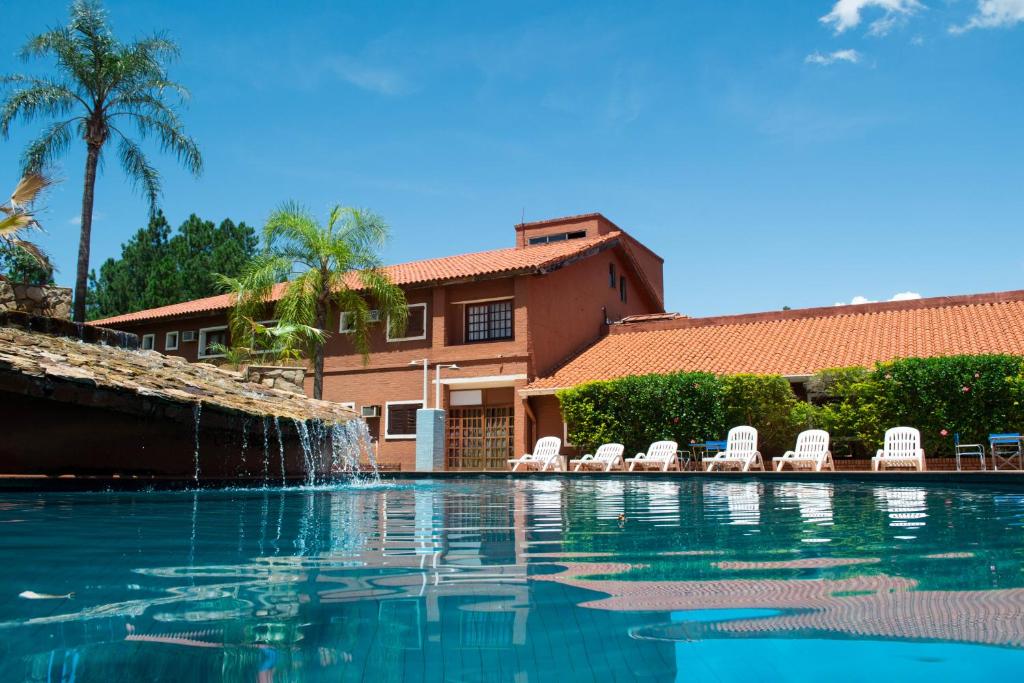 伊瓜苏港伊瓜苏马可波罗套房酒店的一个带椅子的游泳池以及一个喷泉