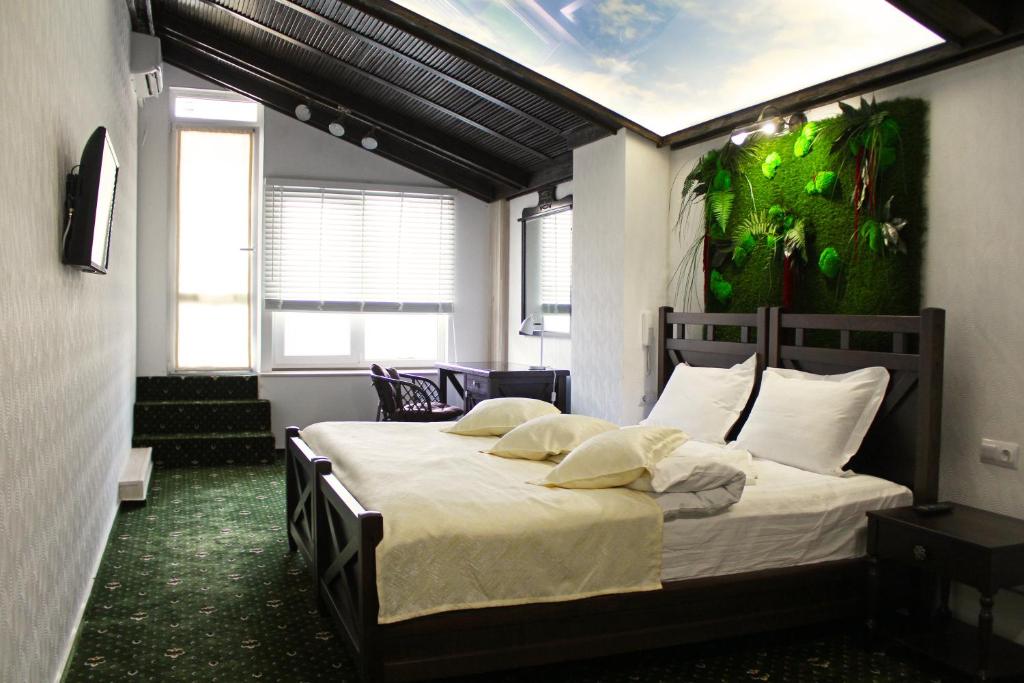 顿河畔罗斯托夫普罗蒙纳精品酒店 的一间卧室配有一张大床,墙上挂着绿色画作