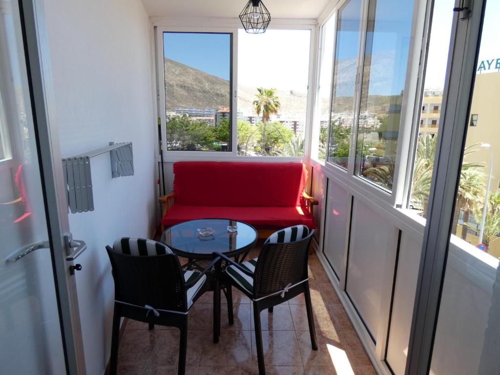 阿罗纳Rosamar Luxury Apartment的阳台配有桌椅和红色沙发。