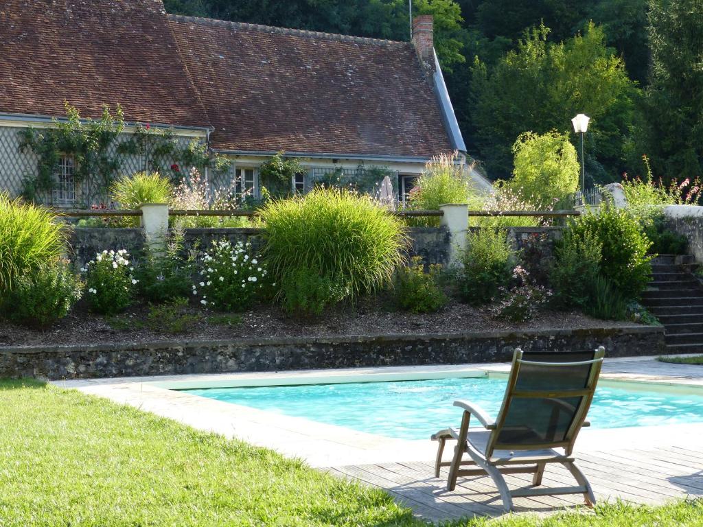 谢尔河畔阿瑟Gite de la Vigneraie的坐在游泳池旁的草地上的椅子