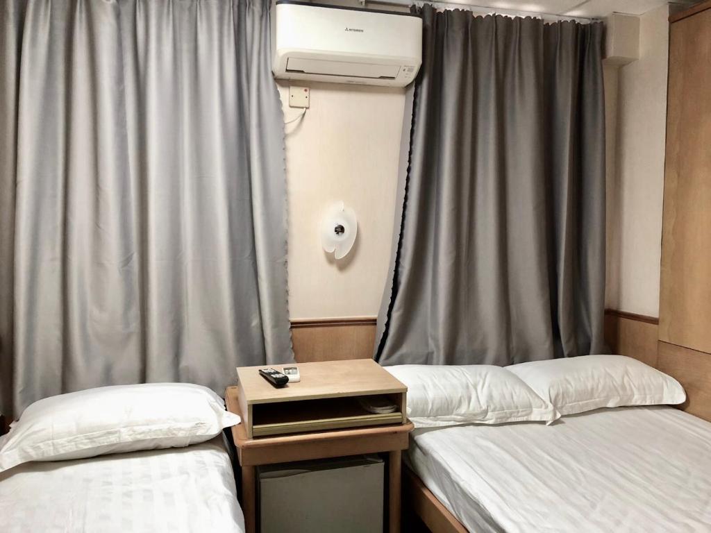 香港祥泰旅馆的客房设有两张床和一个带窗帘的窗户。