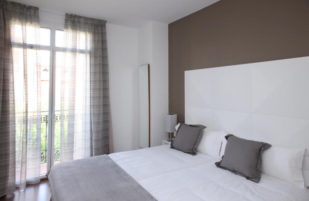 巴塞罗那MH套房公寓式酒店的卧室设有白色的床和大窗户