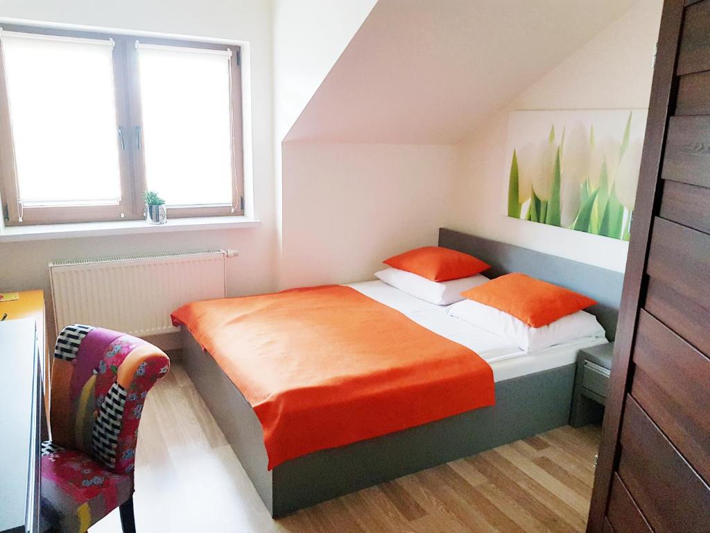 亚斯沃Hotel i Restauracja Pod Skałą Jasło的一间卧室配有带橙色床单和椅子的床