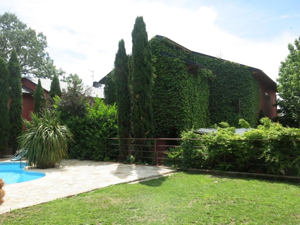 纳瓦塞拉达Chalet Navacerrada Piscina Privada的常春藤覆盖的房屋,设有游泳池