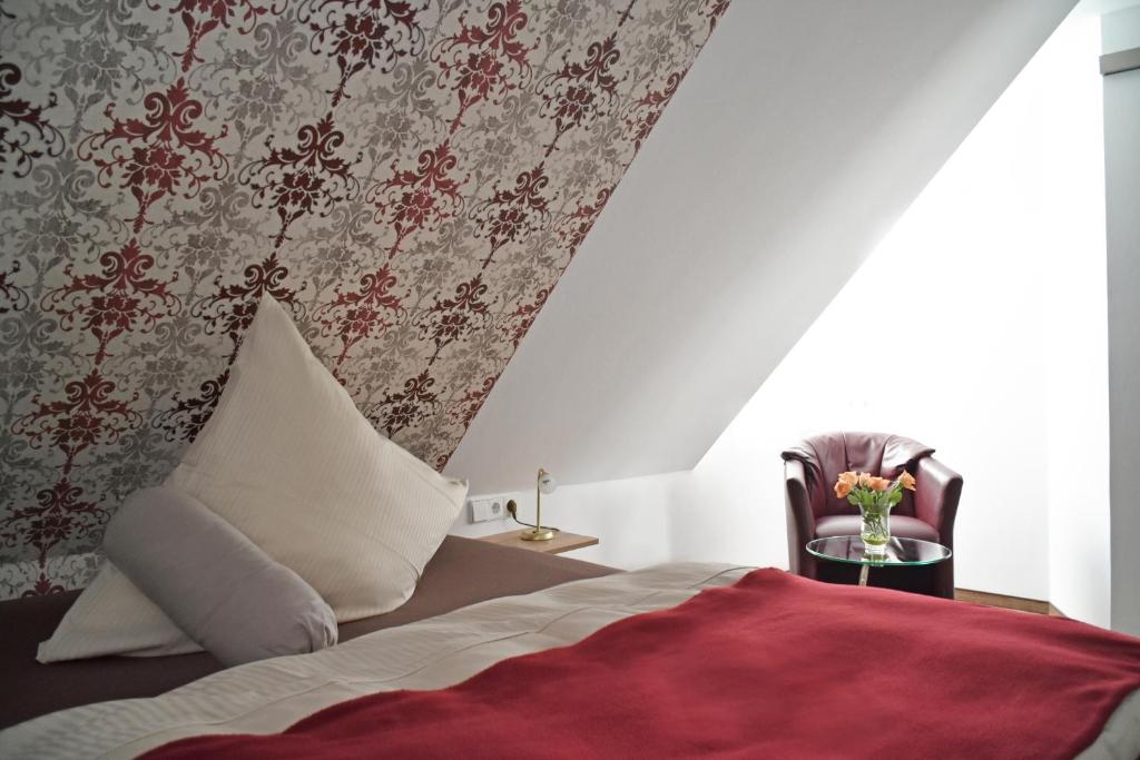 雷宁根Hotel Zur Eisenbahn的一间卧室配有一张带红色毯子和椅子的床