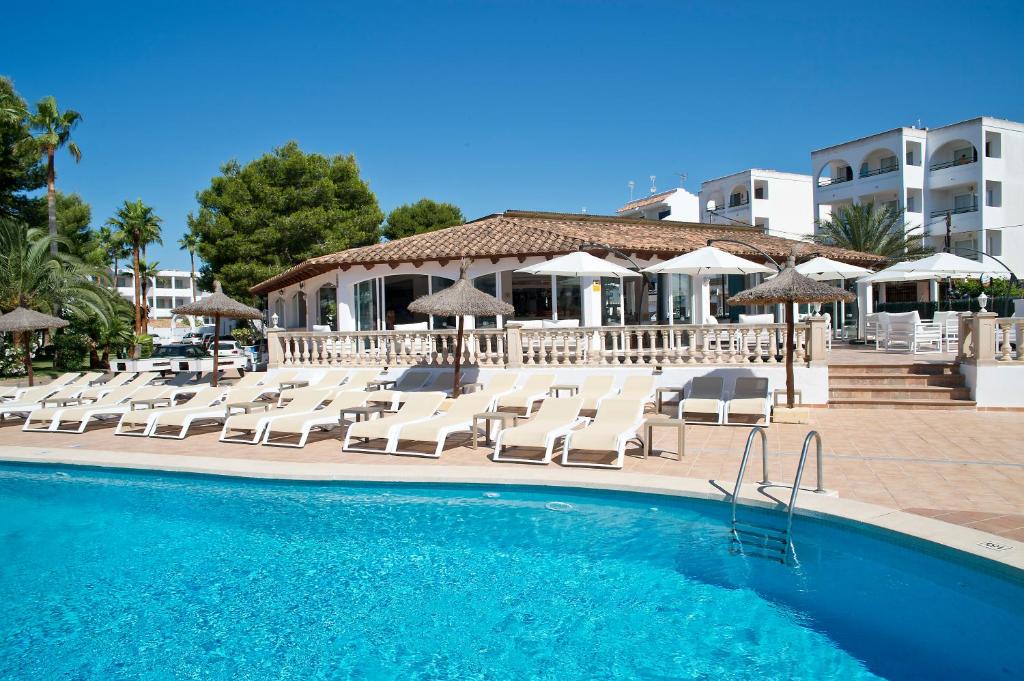 克罗姆港皮埃尔马略卡赛西利亚公寓酒店的一个带躺椅和遮阳伞的游泳池