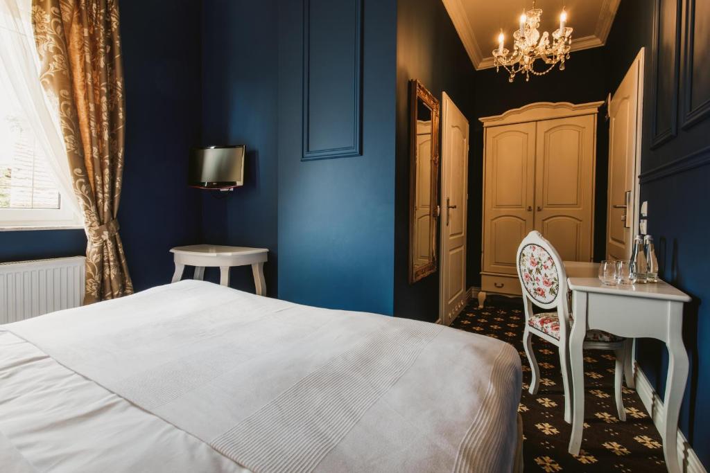 Nowe Kramsko维亚别墅酒店的一间卧室设有蓝色的墙壁、一张床和一张书桌