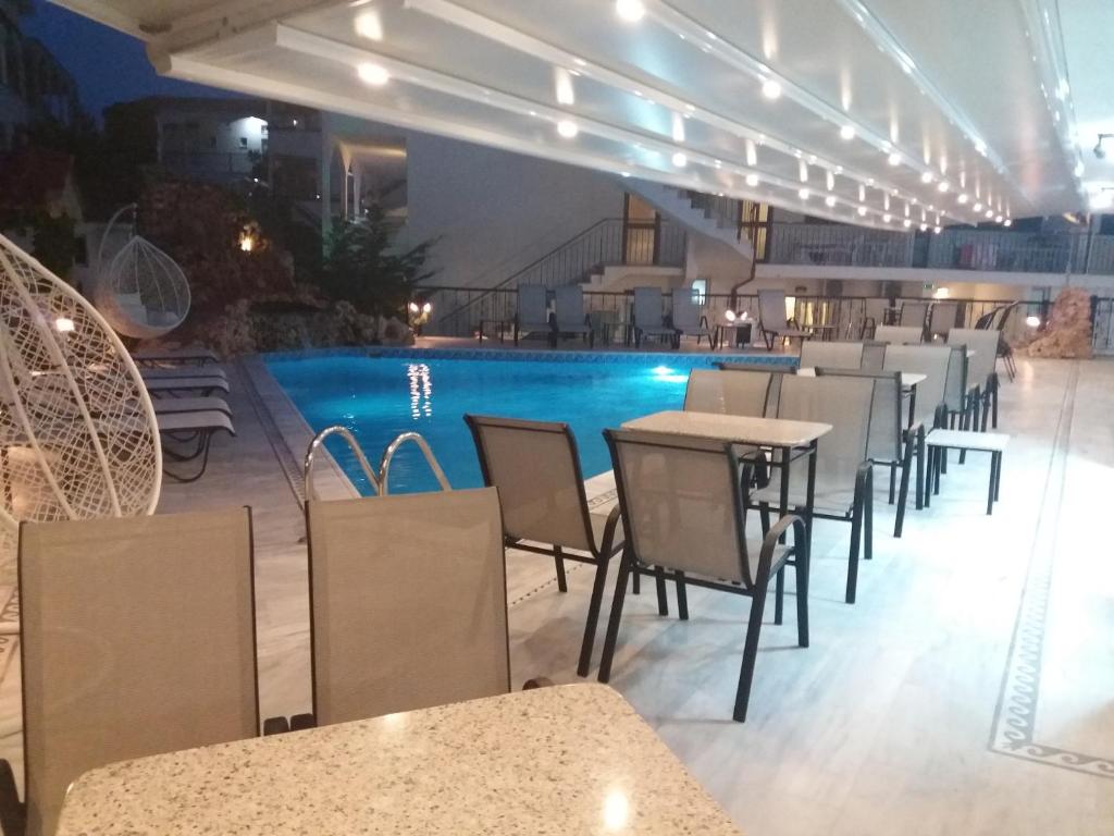 卡尼奥提Pegasus Hotel的一间带游泳池和桌椅的餐厅