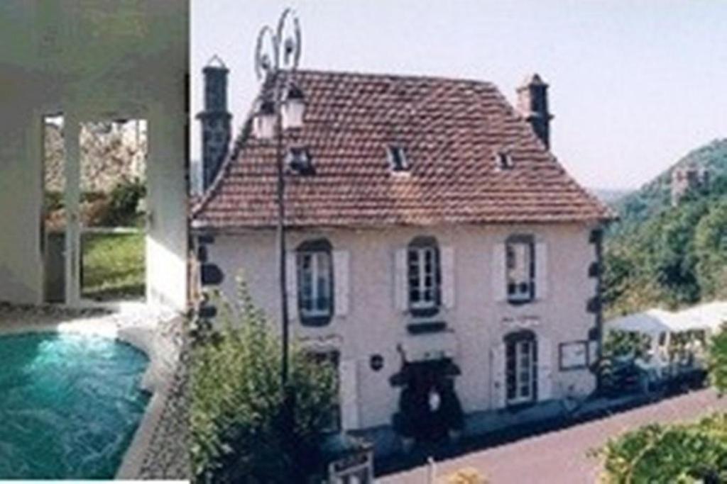 TournemireAuberge Hôtel de Tournemire - Cantal的一座大型白色房子,前面设有一个游泳池