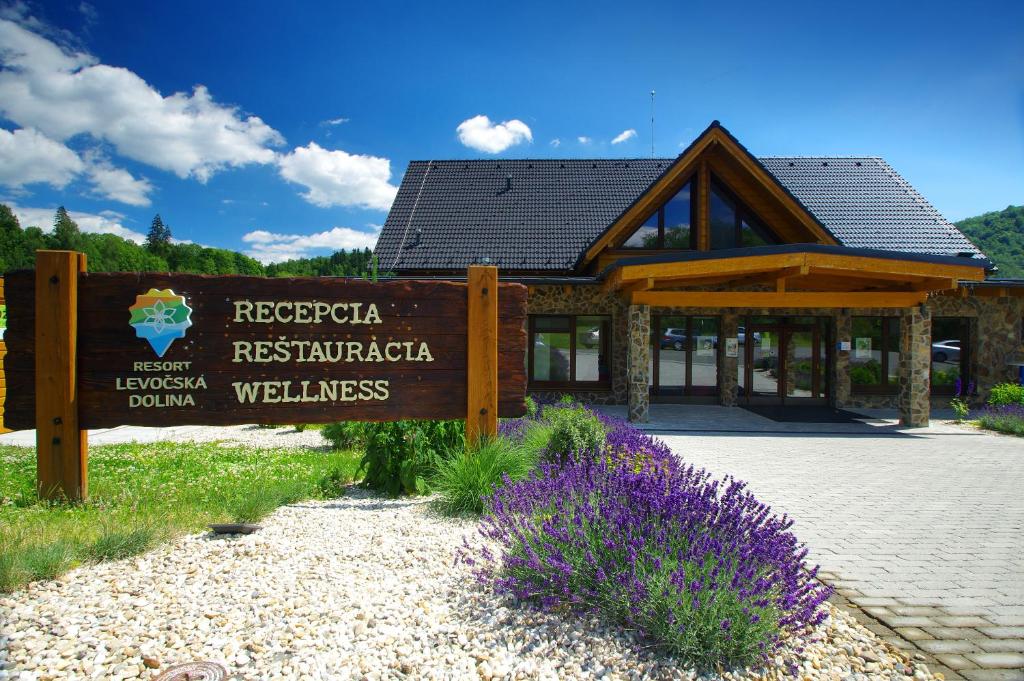 莱沃恰Resort Levočská Dolina的紫色花的建筑前的标志