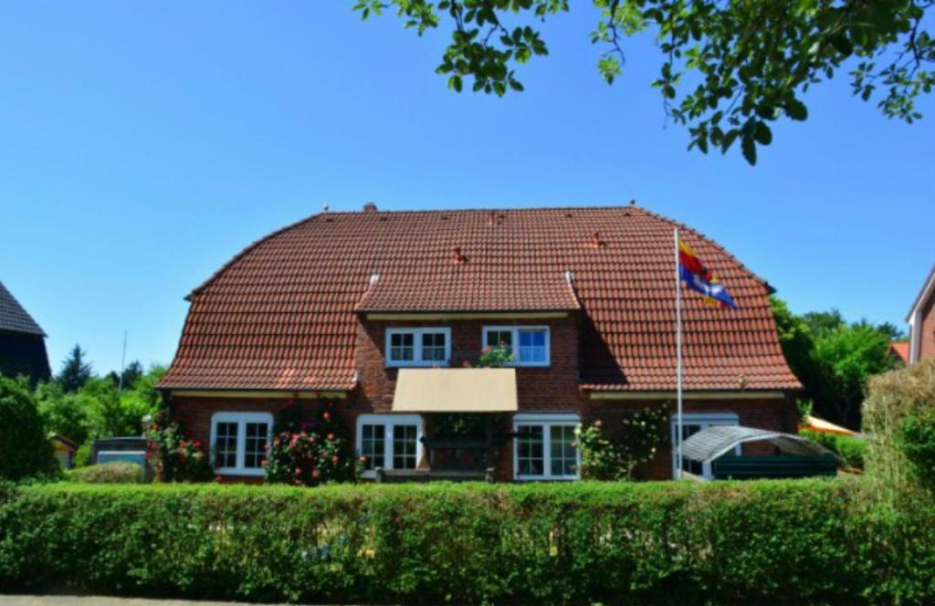 威克奥夫弗尔Landjägerhaus am Südstrand - Wohnung 1 + 3的棕色的房子,有红色的屋顶和旗帜