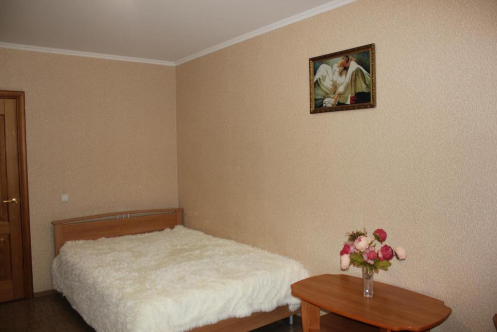 秋明Апартаменты на Пермякова的一间卧室,配有一张床,桌子上放着花瓶