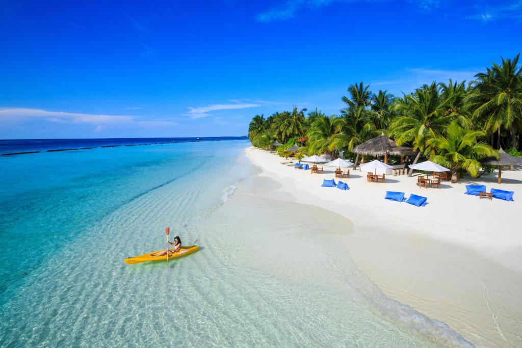 马累Kurumba Maldives的海滩上划着黄色皮艇的人