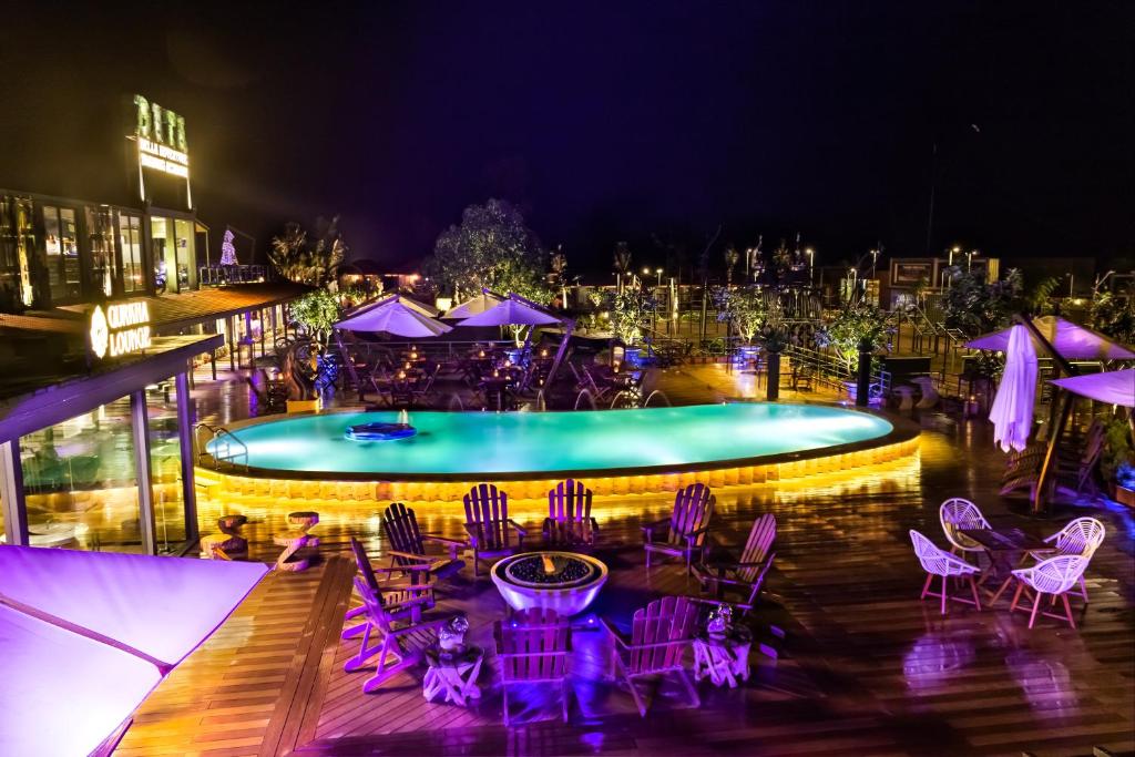 罗纳瓦拉DATA Resort by Della Adventure的一个带紫色桌椅和一组遮阳伞的游泳池