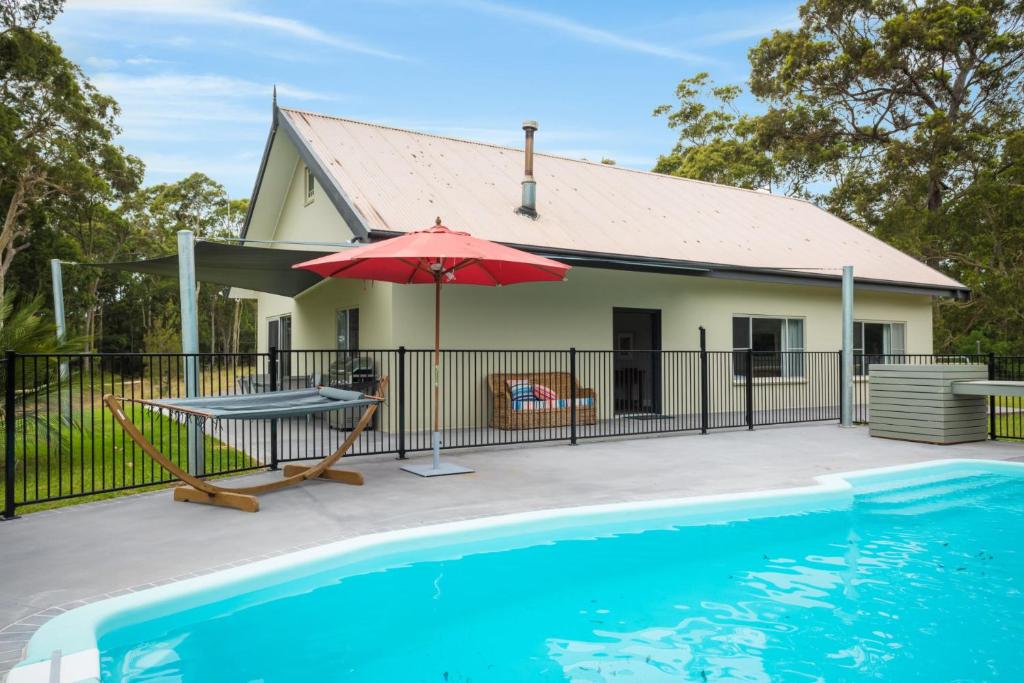 纳鲁马Bush Retreat With Private Pool的一座带游泳池和红伞的房子