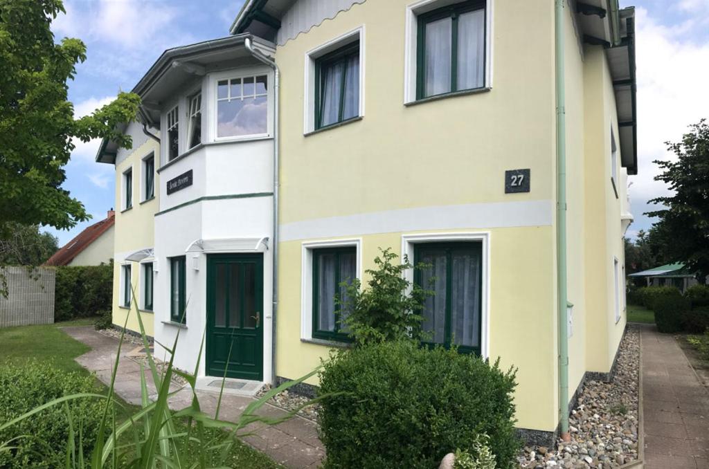 特拉森海德"Villa Seute Deern" Trassenheide, Familie Meutzner的黄色和白色的房子,设有绿门