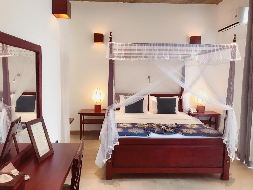 拉维尼亚山科扎锡兰酒店的一间卧室配有天蓬床和镜子