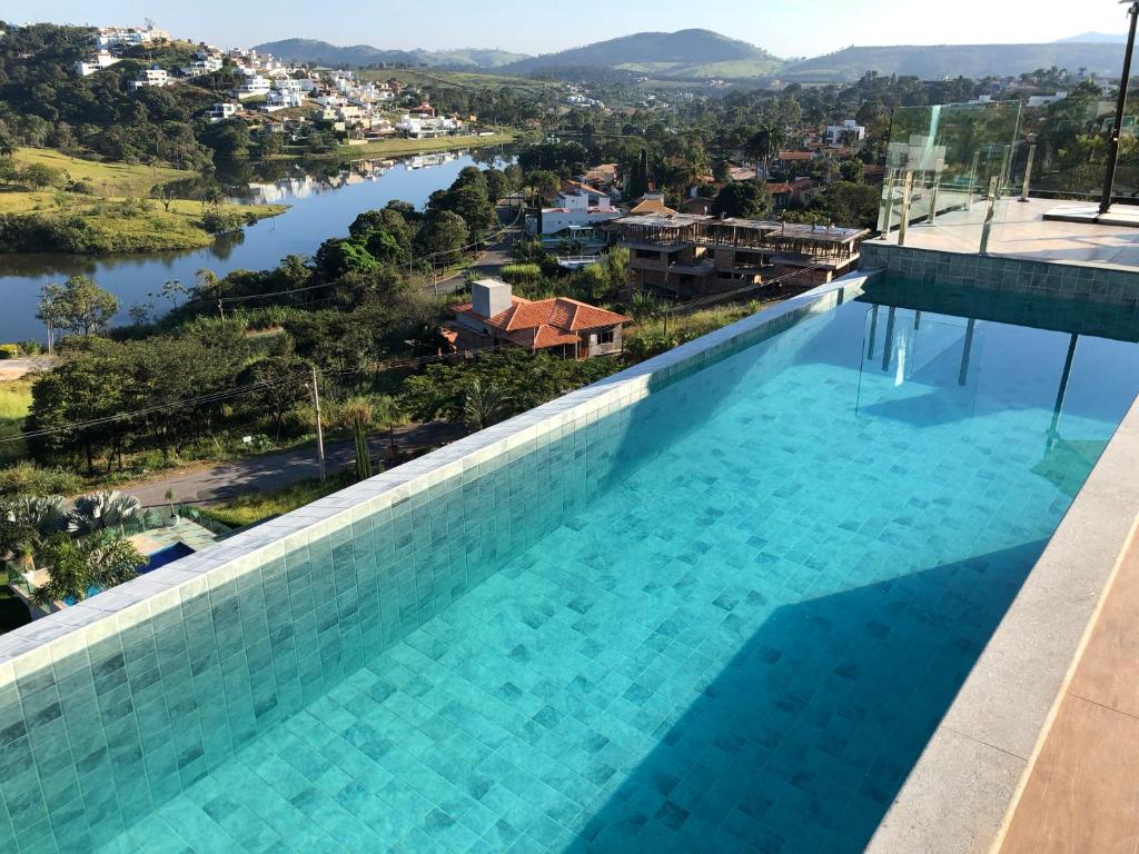 卡皮托利乌Suítes de Luxo Paraíso de Minas Escarpas的享有河流和城市景致的游泳池
