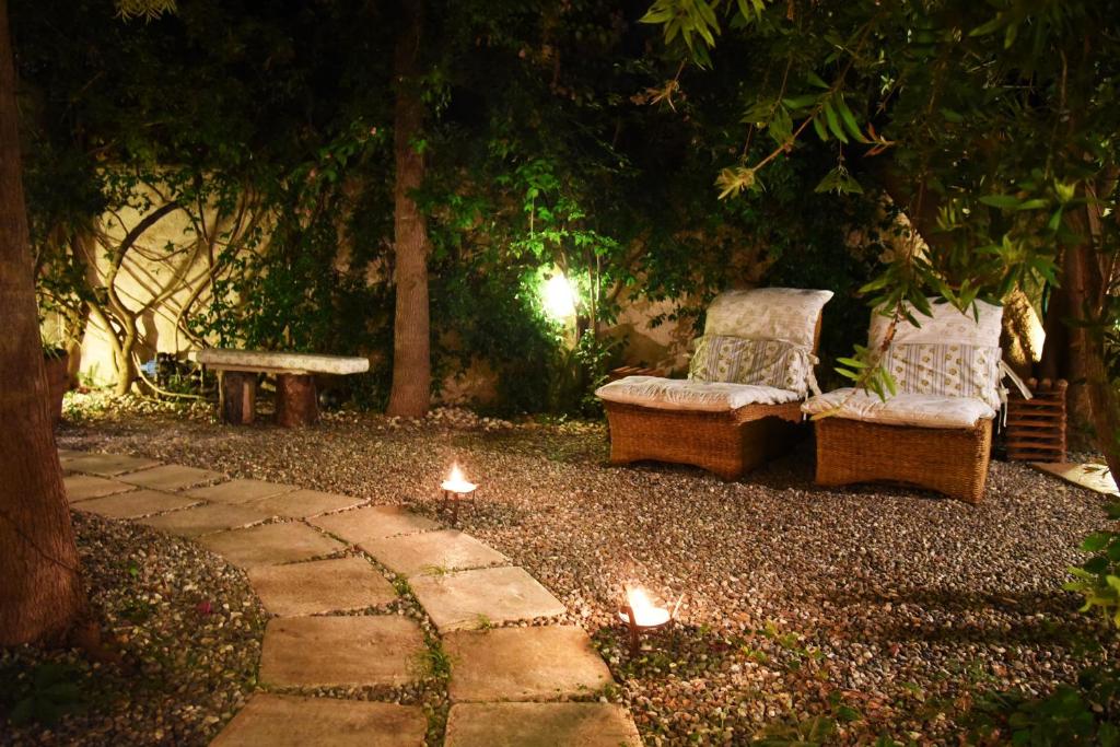 托雷坎内B&B Al Vecchio Glicine的花园内晚上有两把椅子和一张长凳