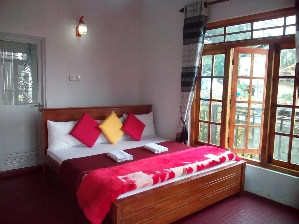 努沃勒埃利耶King's Lodge的一间卧室配有红色和黄色枕头的床
