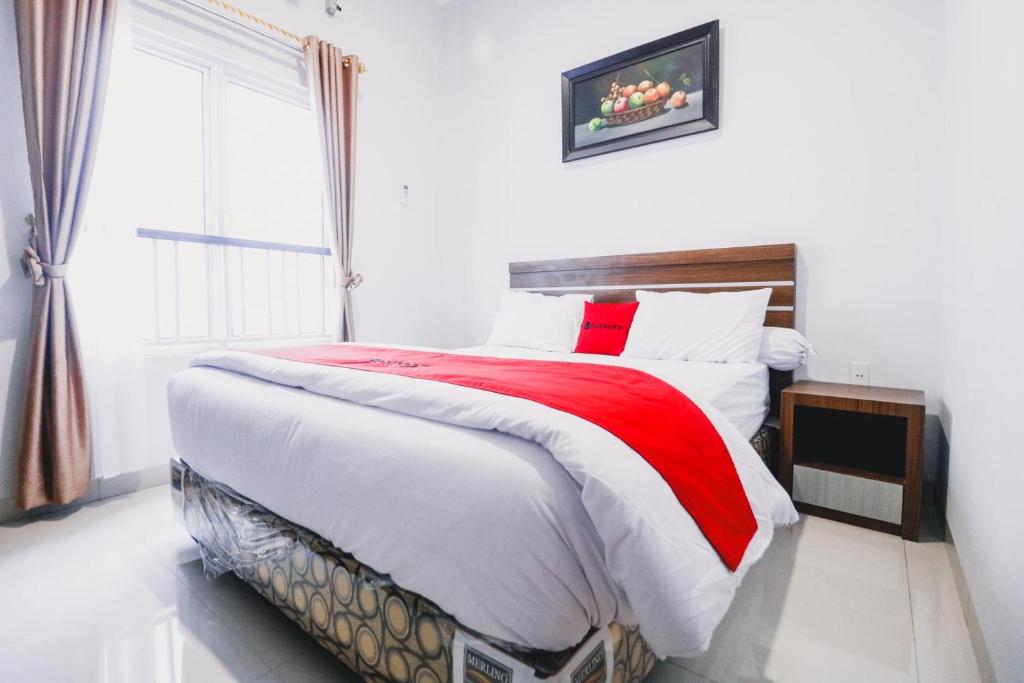 棉兰RedDoorz near Hermes Place Polonia Medan的卧室设有红色和白色的床和窗户。