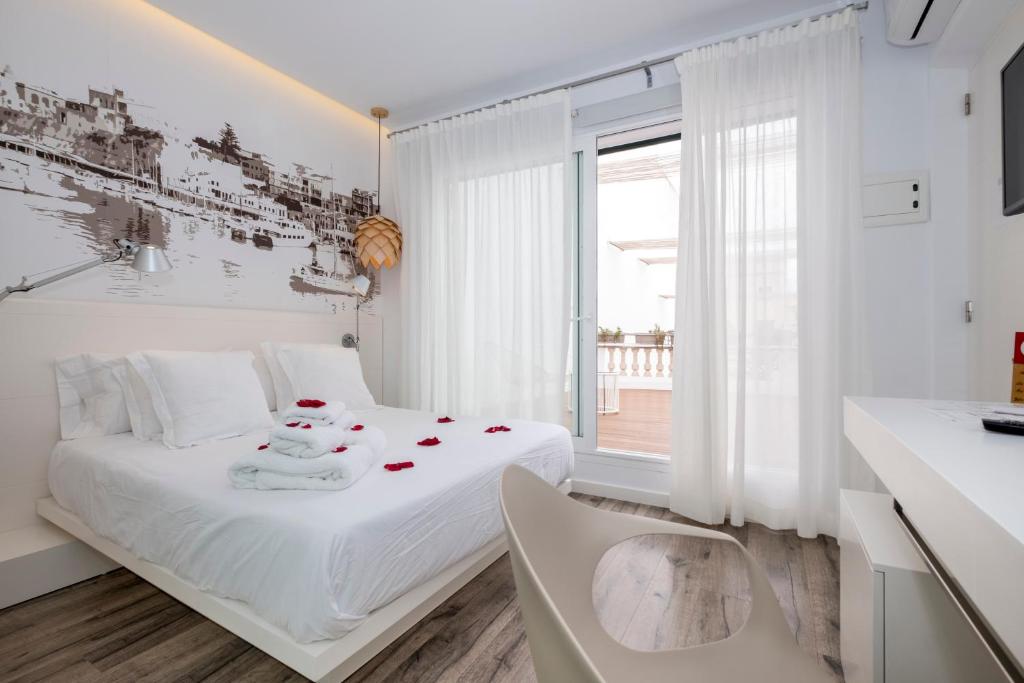 休达德亚Hotel Abril 37的白色的卧室,床上有玫瑰花床