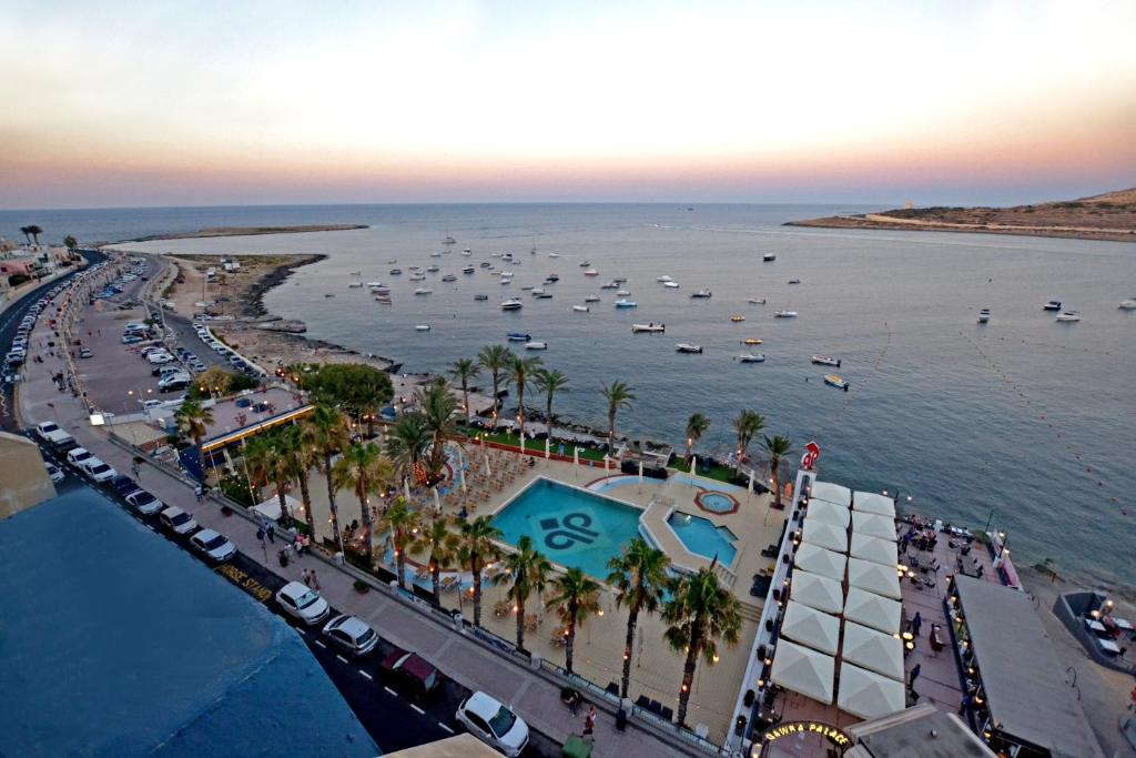 圣保罗湾城QAWRA Palace Resort & SPA的享有海滩的空中景色,在水中划船