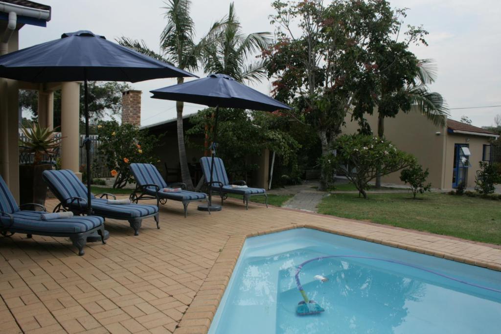普利登堡湾113 on Robberg的房屋旁的游泳池配有椅子和遮阳伞