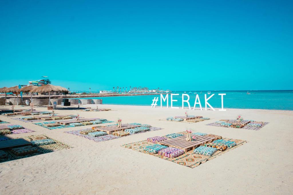赫尔格达Meraki Resort - Adults Only的沙滩上带椅子和遮阳伞的海滩