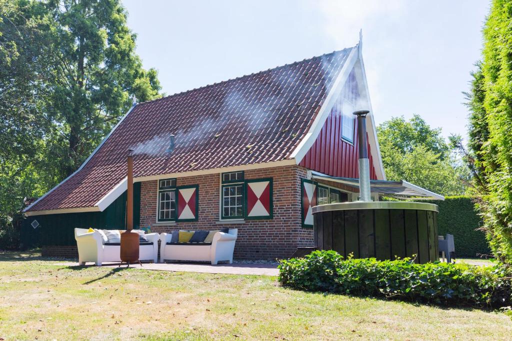 利费尔德De Brittenburg met privé hottub & sauna 4-persoons的砖屋,带红色屋顶,配有沙发