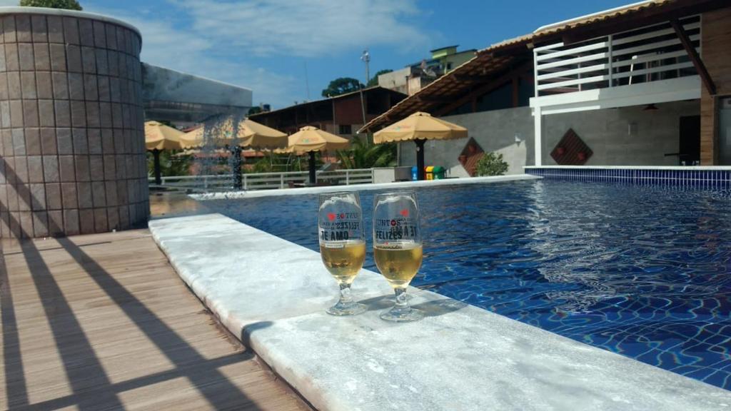 皮帕Pipa's Bay - Flats para temporada的两杯葡萄酒坐在游泳池旁