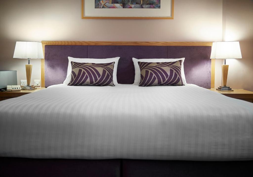 诺斯利The Suites Hotel & Spa Knowsley - Liverpool by Compass Hospitality的一张带两个枕头的大床和一个紫色床头板