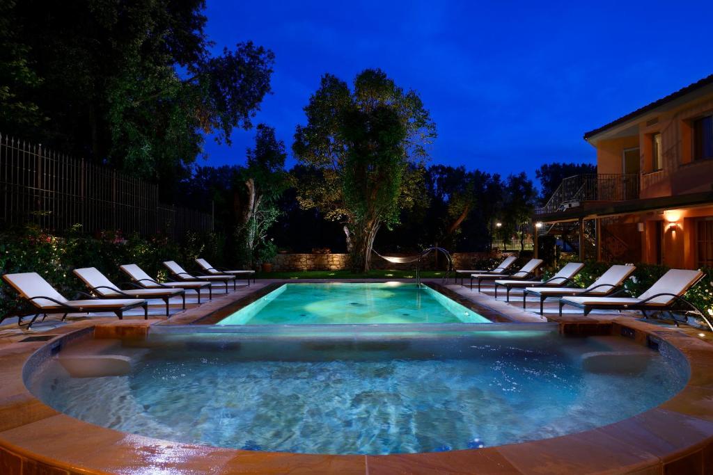 佛罗伦萨维莱苏拉诺酒店的游泳池周围设有躺椅,晚上