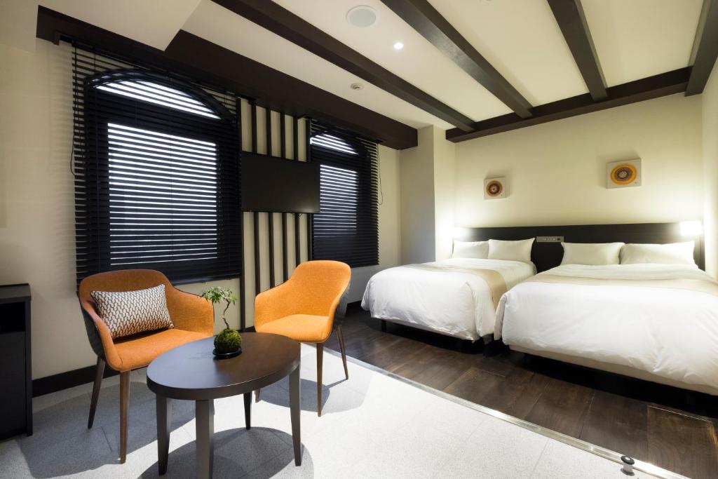 藤泽EN HOTEL Fujisawa的一间卧室配有两张床和一张桌子及椅子