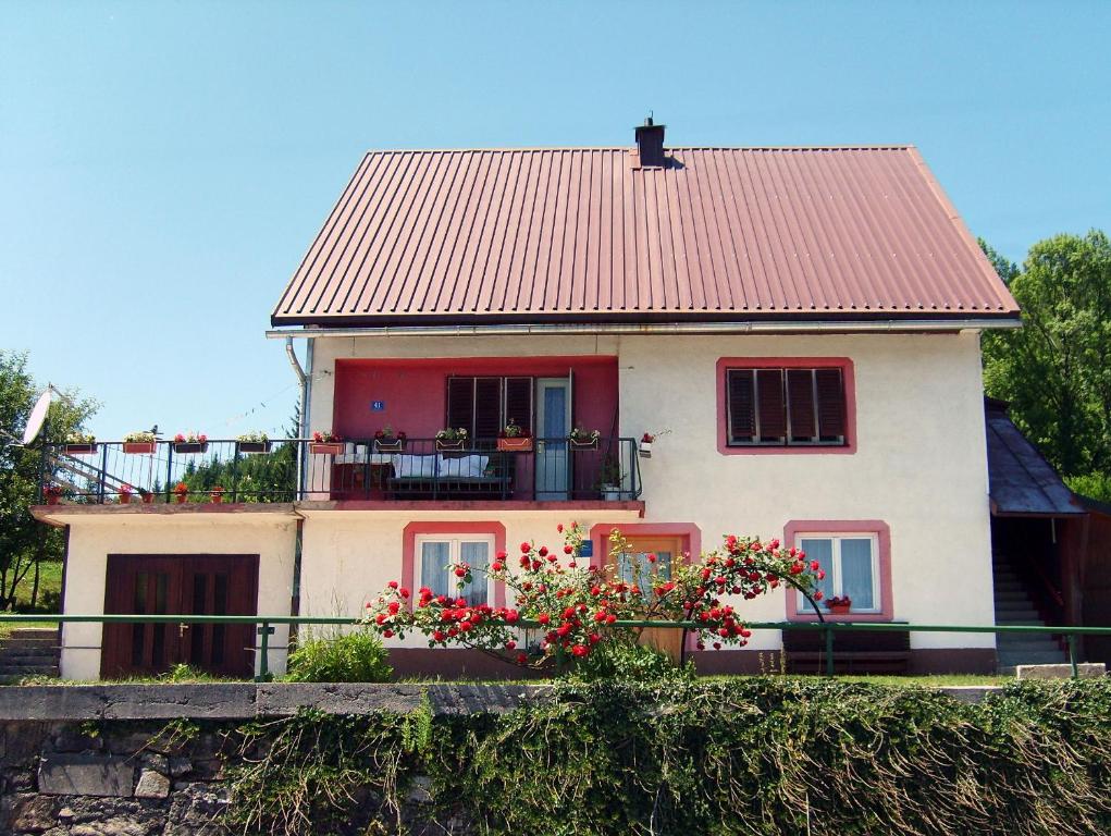 科尔尼鲁格Apartman Štimac的一座房子,前面有红色的屋顶和鲜花